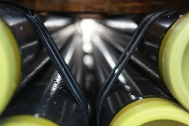 Black ERW carbon steel pipes with beveled ends stacked for B2B export